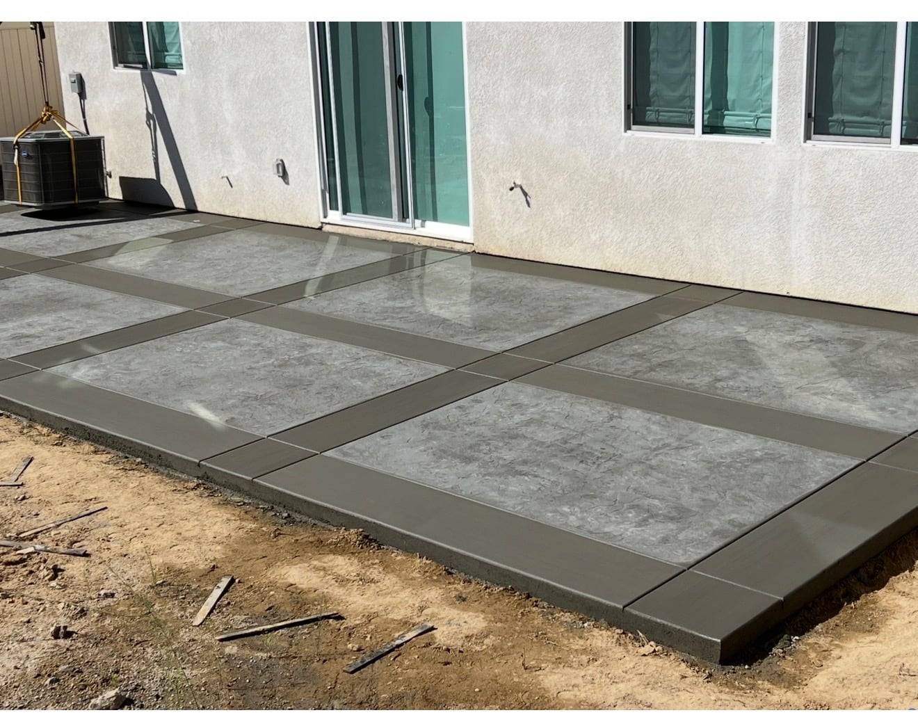 Stamped concrete patio with smooth bordered panels behind a home